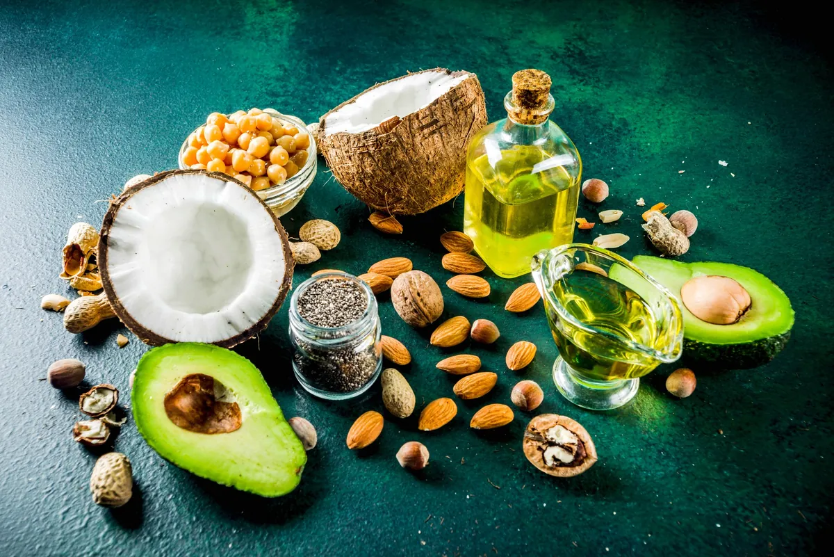 Avocado, coconut, nuts and seeds with bottles of oil